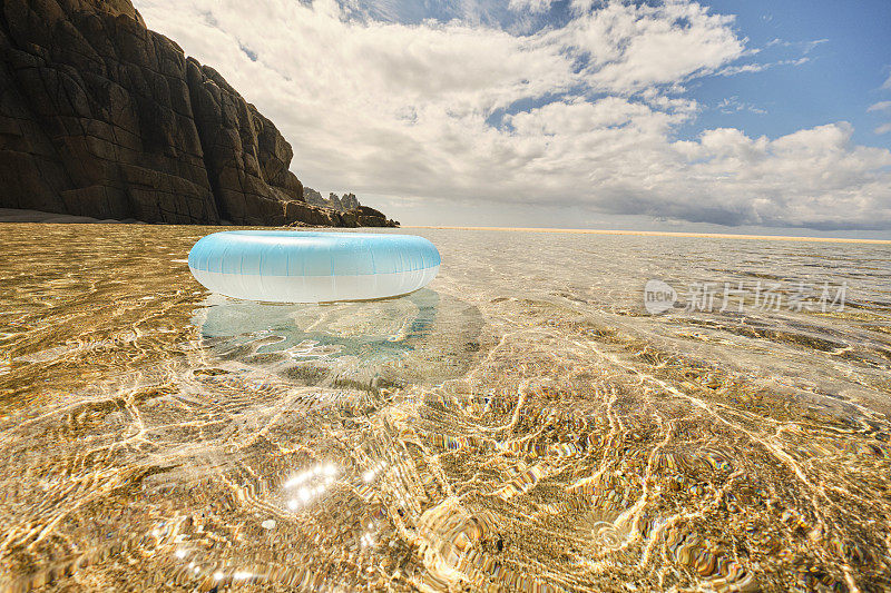 淡蓝色的橡胶圈漂浮在浅水清澈的海面上，在Pedn Vounder海滩，康沃尔在一个田园诗般的阳光明媚的六月天。